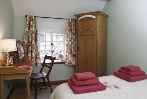 a bedroom with a bed with red towels on it at The Honeypot in Chipping Campden