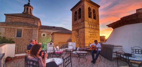 a group of people sitting on a patio with a clock tower at Entre Dos Aguas Hotel Boutique in Toledo