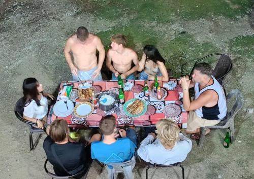 een groep mensen die rond een tafel zitten met eten bij Nias Kristov Surf Camp in Lagudri