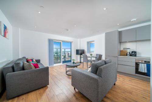 a living room with two chairs and a kitchen at Skyvillion - London River Thames Top Floor Apartments by Woolwich Ferry, Mins to London ExCel, O2 Arena , London City Airport with Parking in London