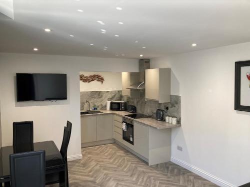 cocina con mesa y TV en la pared en Kimberley Holiday Apartments, en Cleveleys