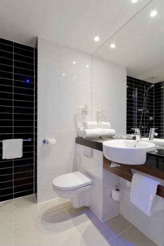 a bathroom with a sink and a toilet and a mirror at Holiday Inn Express Utrecht - Papendorp by IHG in Utrecht