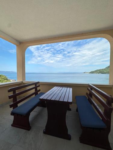 two benches on a balcony with a view of the ocean at Apartments Alać in Drasnice