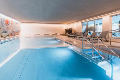 - une piscine d'eau bleue dans un bâtiment dans l'établissement Felbermayer Hotel & AlpineSpa-Montafon, à Gaschurn