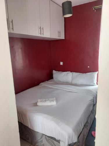 1 cama con sábanas blancas y pared roja en Stylish Studio on Ngong Road, en Nairobi