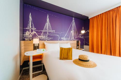 a hotel room with a bed with a straw hat on it at ibis Styles Ancenis Centre in Ancenis