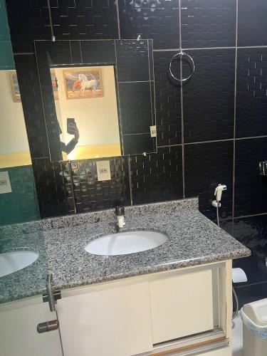 a bathroom with two sinks and a black tiled wall at Versatile Park Hotel in Ponta Porã