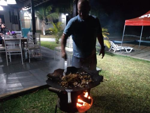 Um homem está a cozinhar comida numa grelha. em Pousada Ferradura em São Pedro