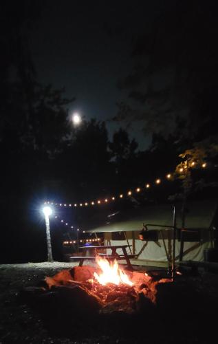 a picnic table with a fire at night at Charming enclave Luxury tent in the woods Tent 3 Bambi's playground in Lenoir