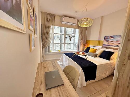 a bedroom with a bed and a table with a laptop on it at Home Time Studios in Florianópolis