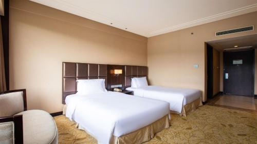 two beds in a hotel room with white sheets at Holiday Inn Mudanjiang by IHG in Mudanjiang