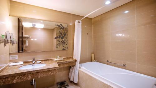 a bathroom with a bath tub and a sink at Holiday Inn Mudanjiang by IHG in Mudanjiang