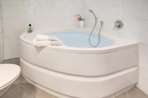 La salle de bains est pourvue d'une baignoire blanche et de toilettes. dans l'établissement VIP Apartment Baden-Baden, à Baden-Baden