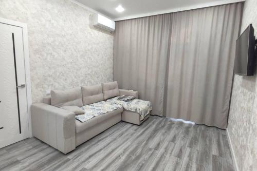sala de estar con sofá y ventana en Люкс апартаменты в ЖК Shanyrak, en Pavlodar