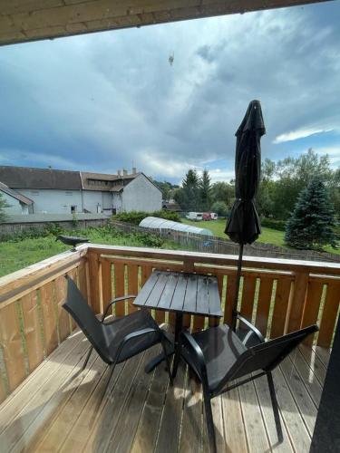 a wooden deck with two chairs and a table and an umbrella at Apartmán Skis in Černá v Pošumaví