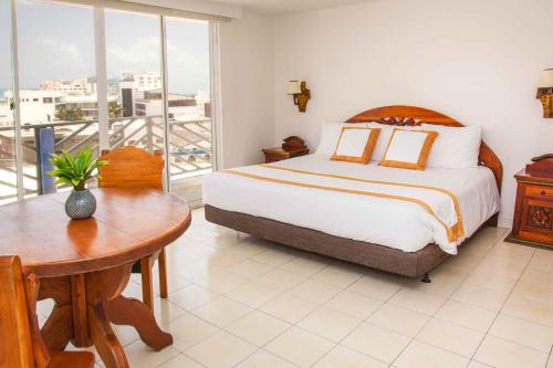a bedroom with a bed and a table and a balcony at Sol Caribe Sea Flower in San Andrés