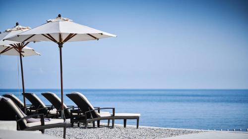 a group of chairs and umbrellas on a beach at Lusso Mare Istria Luxury Beach villa in Savudrija