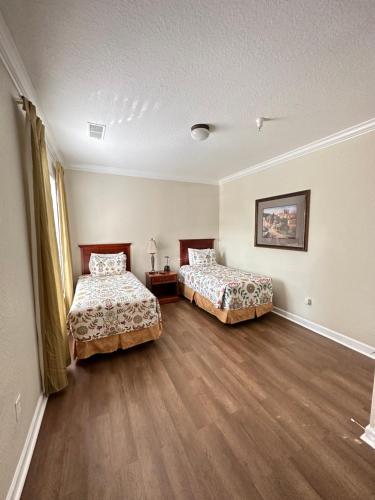 two beds in a room with wooden floors at Gone 2 Florida Vacation Homes in Orlando