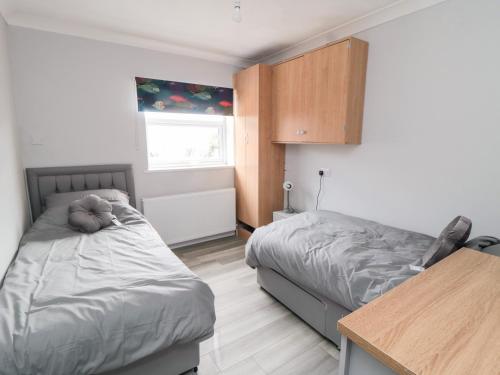 a bedroom with two beds and a table and a window at 10 Southcliffe Drive in Filey