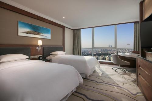 a hotel room with two beds and a desk at Sheraton Nanjing Kingsley Hotel & Towers in Nanjing