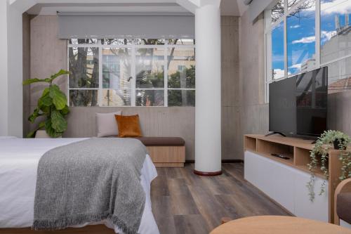 a bedroom with a bed and a flat screen tv at 5Q House Quinta Camacho in Bogotá