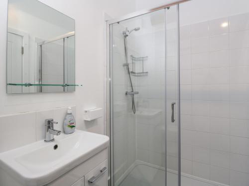 a white bathroom with a shower and a sink at The Old Barn in Witney