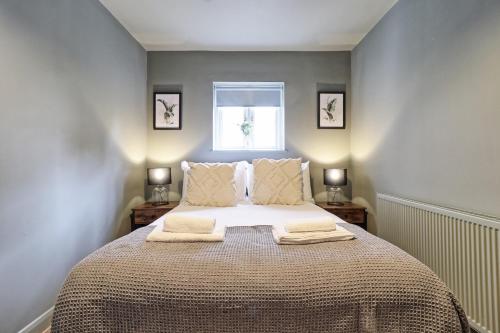 a bedroom with a bed with two towels on it at Plush Nest - Charming One-Bedroom Flat - Southend Stays in Southend-on-Sea