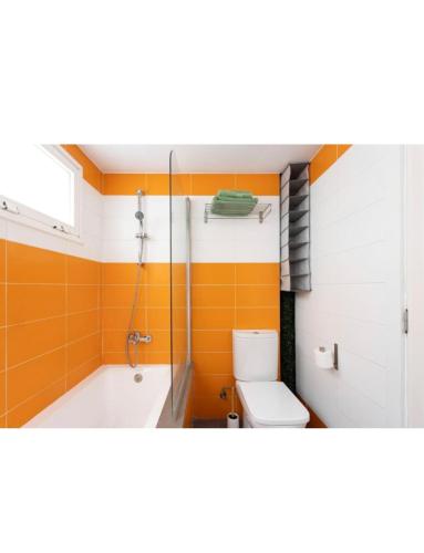 baño de color naranja con bañera y aseo en COCO apartament. en El Médano