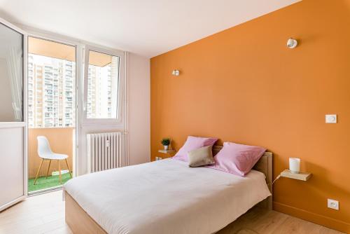 - une chambre avec des murs orange et un lit avec des oreillers roses dans l'établissement APPART COSY - COMME À LA MAISON - ST ETIENNE, à Saint-Étienne