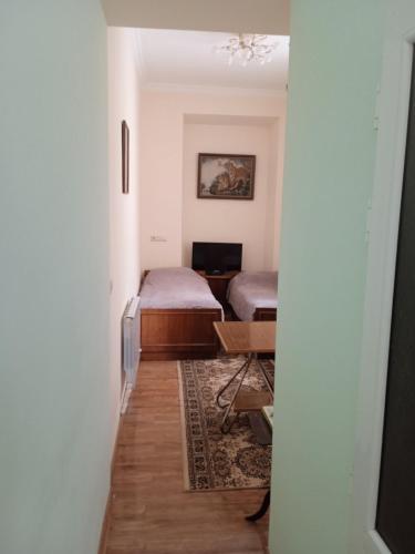 - un couloir avec 2 lits et une table dans une chambre dans l'établissement Уютный дом, à Gyumri
