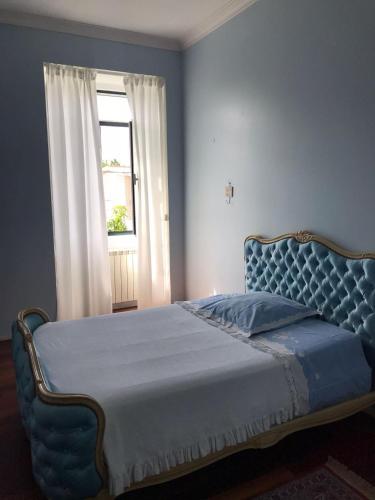a blue bed in a bedroom with a window at Casa Beija-Flor in Mogofores