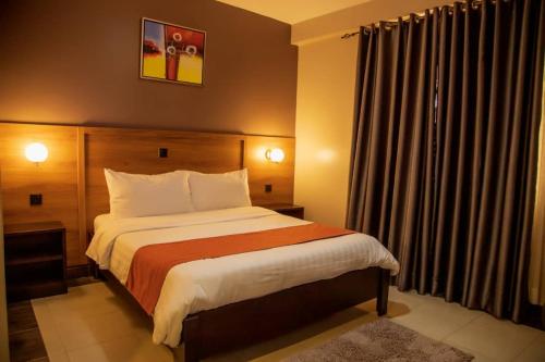 een slaapkamer met een groot bed in een hotelkamer bij Blueberries Hotel in Entebbe