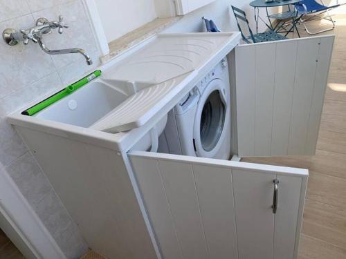 a washing machine in a white kitchen with a sink at Le Giraffe ( n.CIS LE07503191000035725) in Rivabella