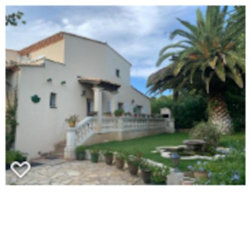 une maison blanche avec une clôture et un palmier dans l'établissement Studio dans villa proche de la plage, à Sète