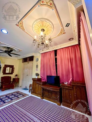Habitación con cortina roja y lámpara de araña. en Harramain Homestay Kuala Krai en Kuala Kerai