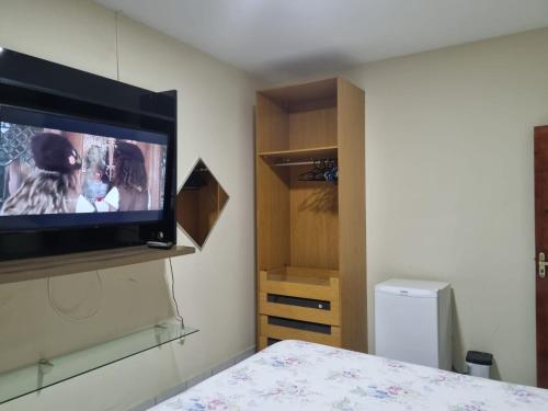 1 dormitorio con TV de pantalla plana en la pared en Sua casa fora de casa, en João Pessoa