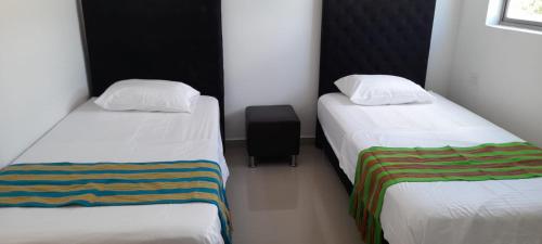 Habitación pequeña con 2 camas y maleta negra en SALINAS PLAZA HOTEL, en Manaure