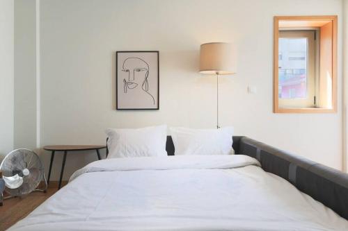 a bedroom with two beds with white sheets and a table at Republica Deluxe Apartment in Vila Nova de Gaia