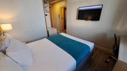 a bedroom with a bed and a flat screen tv at Hotel Diego de Almagro Calama Express in Calama