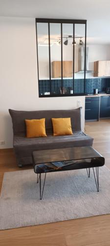 un sofá en la sala de estar con almohadas amarillas en Centre, Soulages, Amphithéâtre - clim balcon parking, en Rodez