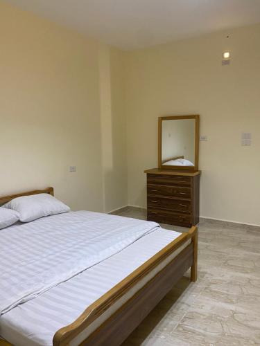 een slaapkamer met een bed, een dressoir en een spiegel bij Darkum Apartment in Wadi Musa