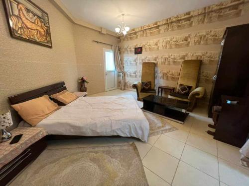 1 Schlafzimmer mit einem großen Bett und 2 Stühlen in der Unterkunft شقة مفروشة دبي in Ajman 