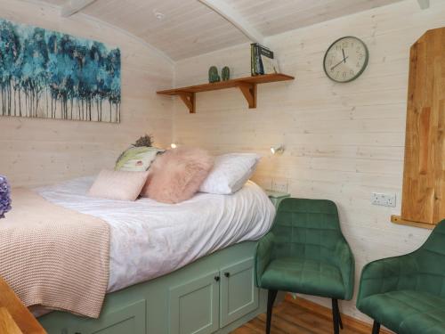 uma cama num quarto com um relógio na parede em Lottie's Hut em Okehampton
