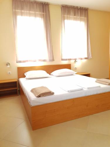a large bed in a room with two windows at Villa Nikoli in Nesebar