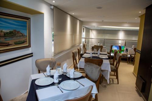 ein Restaurant mit Tischen und Stühlen und einem Gemälde an der Wand in der Unterkunft Malak Hotel in Rabat