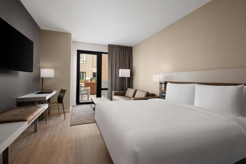 Habitación de hotel con cama blanca grande y sofá en AC Hotel by Marriott Santa Rosa Sonoma Wine Country, en Santa Rosa