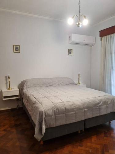 1 dormitorio blanco con 1 cama y 2 mesas en Amplio dpto. Peatonal Mendoza en Mendoza