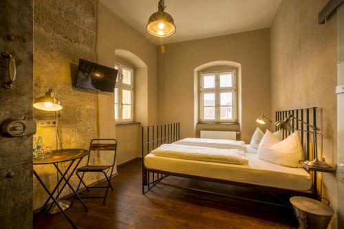 a bedroom with a bed and a table in it at Knast-Hotel Fronfeste in Amberg