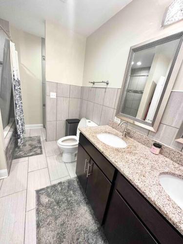 a bathroom with two sinks and a toilet and a mirror at Beautifully Renovated House 10 mins from Downtown in Chicago