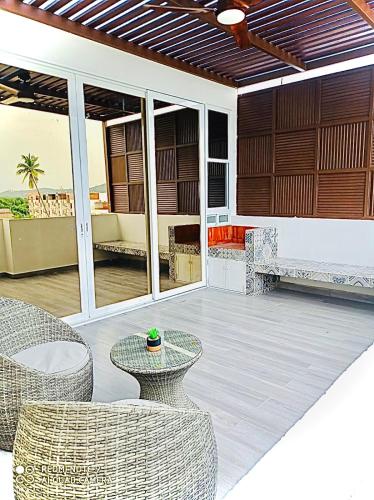 a patio with wicker chairs and tables and glass doors at Nuevo penthouse con terraza privada, alberca , area infantil y pet friendly in Manzanillo